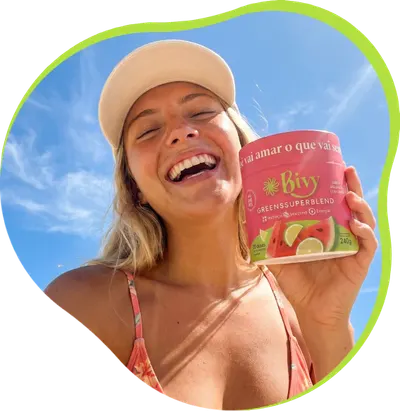 Mulher sorrindo segurando um pote de Bivy Greens Super Blend